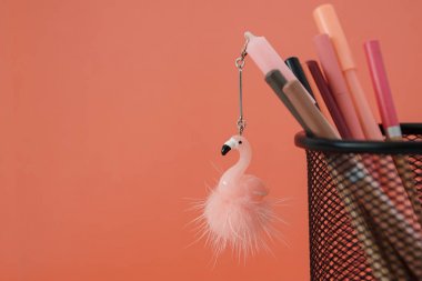 Kırtasiye. Okula geri dön. Ücretsiz kopya alanı ile mercan renkli arka plan üzerinde sepetflamingo oyuncak ve kalemler ile Kalem