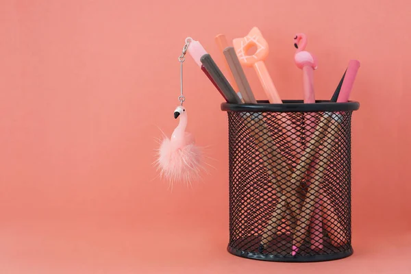 Kırtasiye. Okula geri dön. Ücretsiz kopya alanı ile mercan renkli arka plan üzerinde sepetflamingolar ve kalemler ile Kalemler