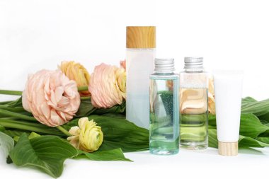 Sarı pembe ranunculus çiçek ve yeşil yaprakları arka plan üzerinde sıvı ile yeniden kullanılabilir şişeler