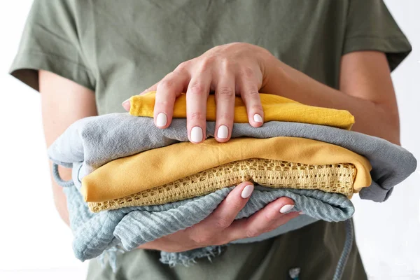 Stack of clothes in yellow green colors in woman s hands on white background — Stock Photo, Image