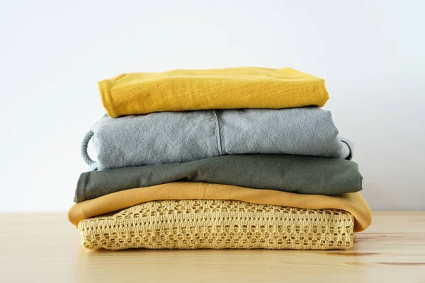 Stack of clothes in yellow green gamma on wooden table — Stock Photo, Image
