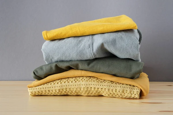 Stack of clothes on wooden table and grey background isolation — Stock Photo, Image