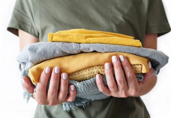 Stack of clothes in woman s hands on white background isolation — Stock Photo, Image