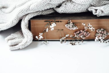 Yer imleri olarak kır çiçeklerinin ve beyaz arka planda sıcak süveterin olduğu eski bir kitap.