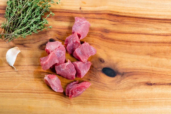 Raw lean diced beef on chopping board with herbs