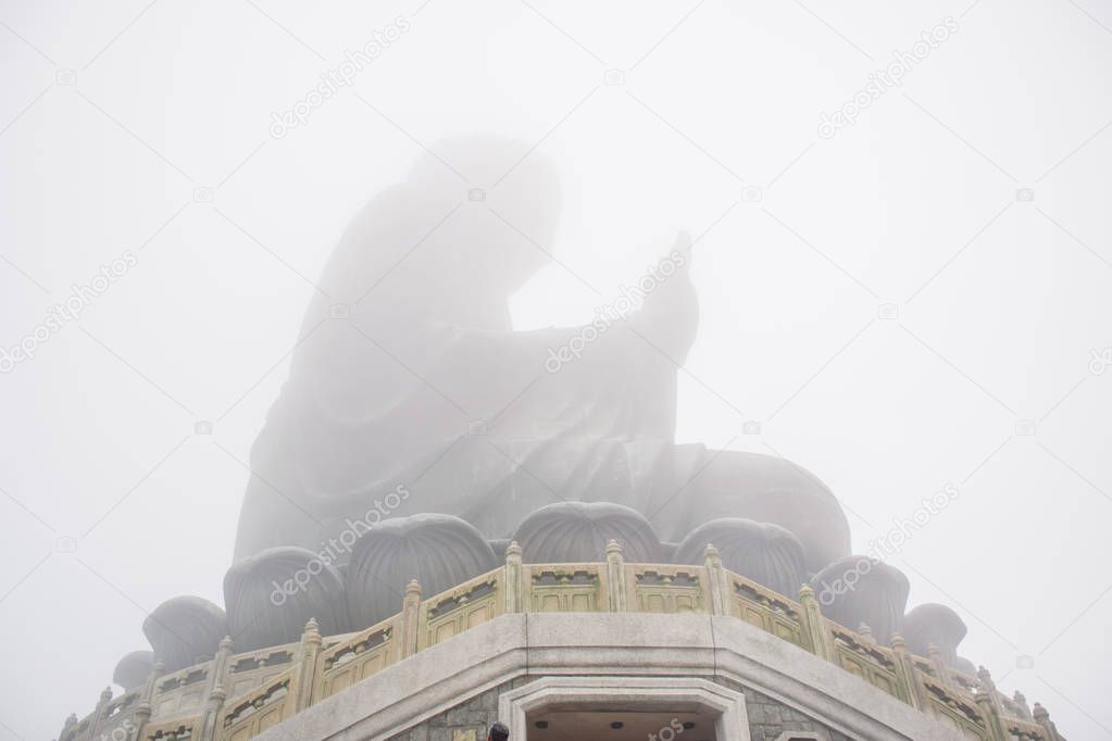 The enormous Tian Tan Buddha statue in the middle of the fog at high mountain near Po Lin Monastery, Lantau Island, Hong Kong