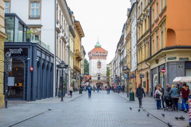 Florianska caddesinde arka planda St. Florian 's Gate ile yürüyen turistler, Polonya' nın Krakow Eski Kasabası 'nın ana caddesi.