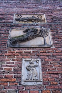 Amsterdam, Hollanda ve Avrupa 'nın tarihi merkezinde tuğla ve taş tabletlere bakan eski bir tuğla duvar.