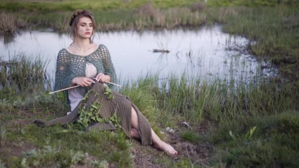 Cuento de hadas. La encantadora chica sentada en la orilla del lago de hadas. Tejer — Vídeo de stock