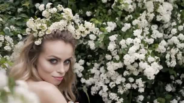 Primavera beleza jovem mulher desfrutando da natureza na primavera, menina bonita feliz no jardim com árvores florescentes. Sorrindo Modelo menina cheirando flores flor — Vídeo de Stock