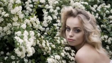 Makyajlı beyaz gelinlikli sarışın gelin. Gelinlikli gelinin düğün günü. Güzel kadın ve çiçekler. Moda sarışın model içeride. Beyaz gelinlikli modelin güzel portresi.