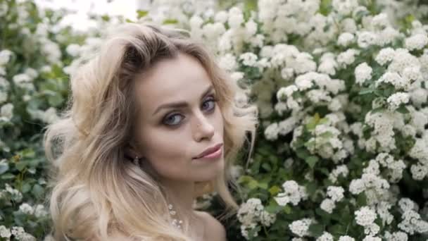 Blond brud i mode vit bröllopsklänning med makeup. Bröllopsdag av brud i brudklänning. Skönhetskvinna och blommor. Mode blond modell inomhus. Skönhetsporträtt av modell i vit brudklänning — Stockvideo