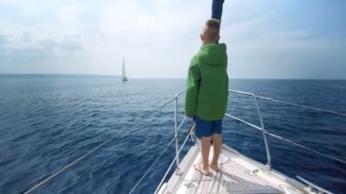 Küçük çocuk yat yay üzerinde duruyor ve yol gösterir