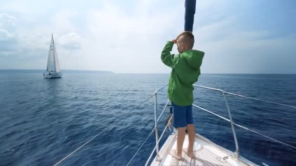 Liten pojke står på fören på båten och visar vägen — Stockvideo