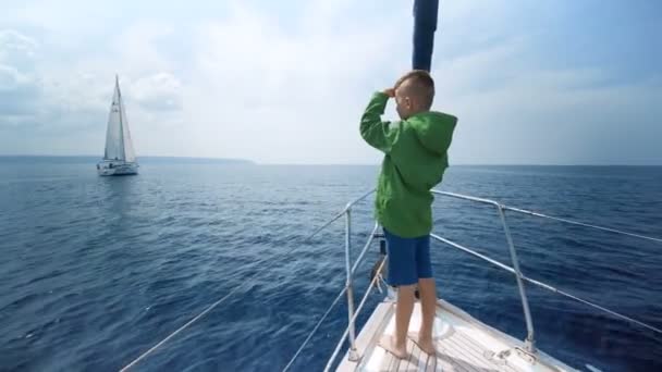 Pequeño niño se para en la proa del yate y muestra el camino — Vídeo de stock