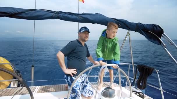 Il padre insegna a suo figlio a guidare lo yacht. Giovane capitano — Video Stock