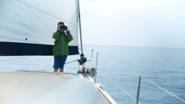 Pequeño niño se para en un yate y mira en un binocular — Vídeo de stock