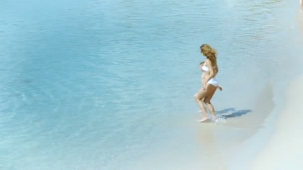 Mãe brincando com seu filhinho e correndo no mar na praia tropical — Vídeo de Stock