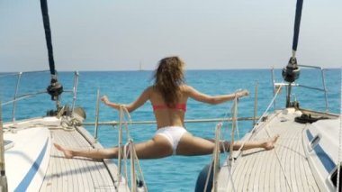 Yakın çekim Shot Yelkenli Yat üzerinde Yoga yaparken zinde bir genç kadın. Arka plan güzel sakin deniz ve açık güneşli gökyüzü