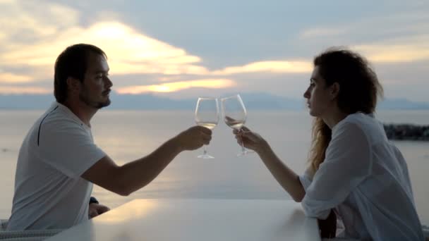 Ευτυχούς ζεύγους που γιορτάζει με ένα ποτήρι λευκό κρασί στην παραλία το ηλιοβασίλεμα — Αρχείο Βίντεο