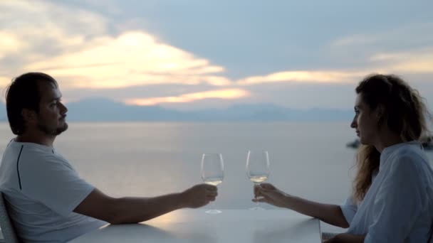 Ευτυχούς ζεύγους που γιορτάζει με ένα ποτήρι λευκό κρασί στην παραλία το ηλιοβασίλεμα — Αρχείο Βίντεο