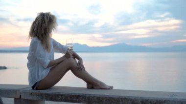 Beyaz şarap yudumlayarak ve manzarayı bir güzel altın yaz günbatımı kadın.