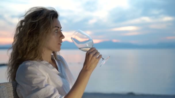 Vrouw nippen van witte wijn en genieten van het Uitzicht van een prachtige gouden zomer zonsondergang. — Stockvideo