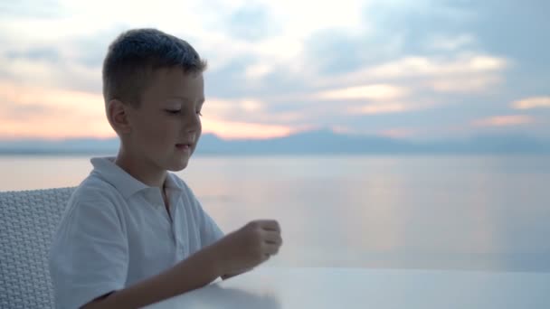 Nahaufnahme Kind Junge hält Hand und isst Kekse am Strand — Stockvideo