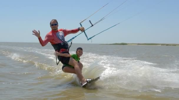 Movimento lento. Papai e seu filho montam no kitesurf juntos — Vídeo de Stock