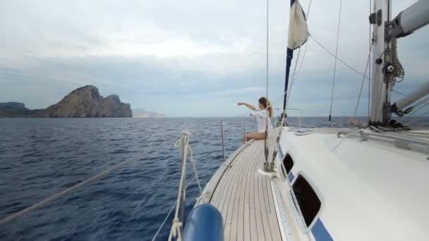 Mooi meisje in de zwembroek zit op de boeg van de jacht en sunbaths in de zee — Stockvideo