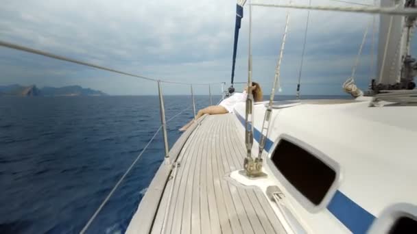 Menina sentada na proa do barco à vela no mar . — Vídeo de Stock