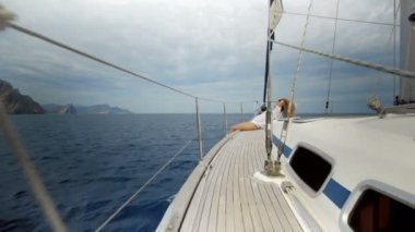 Denizde Yelkenli tekne yay üzerinde oturan kız.