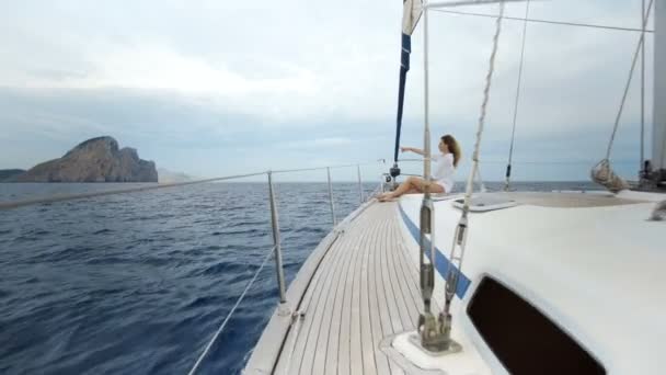 Belle fille en maillot de bain s'assoit sur l'avant du yacht et bains de soleil dans la mer — Video