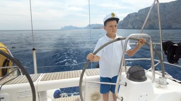 Kleine Kinder Kapitän am Steuer einer Segeljacht während der Regatta. — Stockvideo