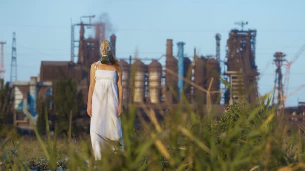 Donna in una maschera antigas su uno sfondo di tubi fumosi di una fabbrica — Video Stock