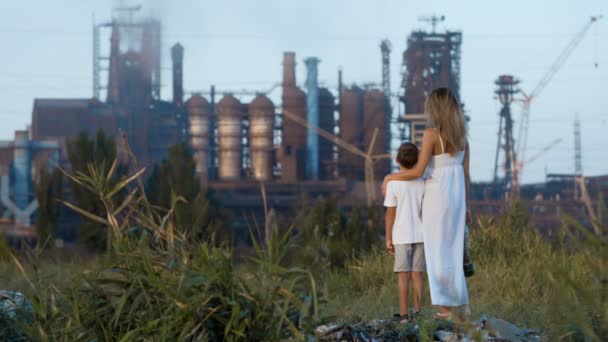 Mamá y su hijo en una máscara de gas de pie en el fondo de una fábrica y pipas de fumar — Vídeos de Stock