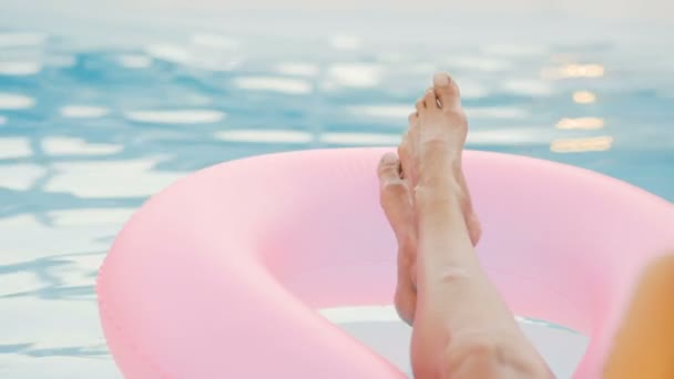 Девушка в бассейне плавает на надувном пончике розового цвета — стоковое видео