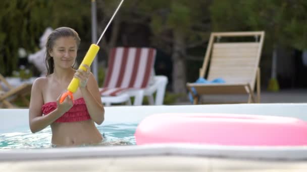 Boldog lány pihentető-úszó felfújható rózsaszín fánk. Fiatal nő a bikini élvezi a nyaralás ivott koktélt a medence rózsaszín floatie — Stock videók