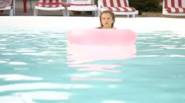 Mutlu kız şişme pembe halka float rahatlatıcı. Yaz tatili havuzu pembe floatie üzerinde kokteyl içme zevk Bikini genç kadın