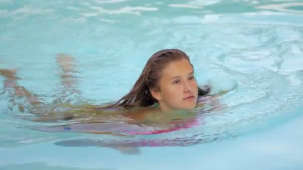 Szczęśliwa dziewczyna na relaksujący na float nadmuchiwane pączek różowy. Młoda kobieta w bikini korzystających lato wakacje picia koktajli na różowy floatie w basenie — Wideo stockowe