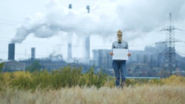 Kız bir arka planda bir fabrikanın dumanlı boru gaz maskeli