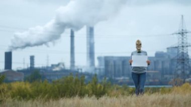 Kız bir arka planda bir fabrikanın dumanlı boru gaz maskeli