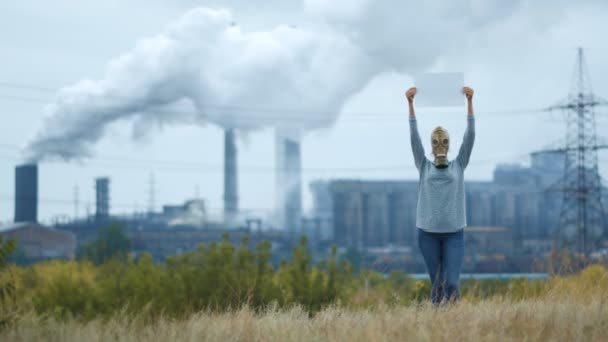 Vrouw in een gasmasker op een achtergrond van rokerige buizen van een fabriek — Stockvideo