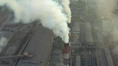 Büyük kırmızı ve beyaz boru kalın beyaz bir duman ile organize sanayi bölgesinde güneş aksine fabrika borudan dökülür. Havadan görünümü