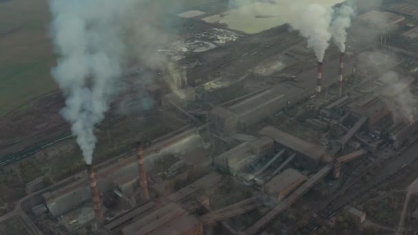 Βιομηχανική ζώνη με ένα μεγάλο κόκκινο και λευκό σωλήνα παχύ λευκό καπνό χύνεται από το σωλήνα εργοστάσιο, σε αντίθεση με τον ήλιο. Εναέρια άποψη — Αρχείο Βίντεο