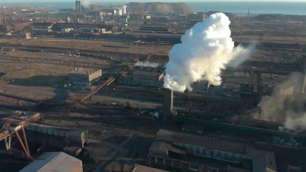 La zone industrielle avec un grand tuyau rouge et blanc épaisse fumée blanche est versée du tuyau d'usine contrairement au soleil. Pollution de l'environnement : une pipe à fumée. Vue aérienne — Video