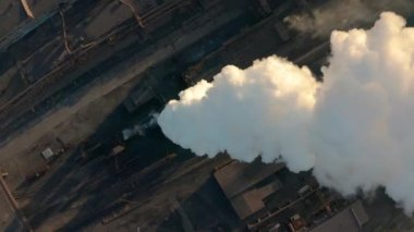 Güneş 'in aksine fabrika borusundan büyük, kırmızı ve beyaz bir boruyla sanayi bölgesi dökülüyor. Çevrenin kirliliği: dumanlı bir pipo. Hava görünümü