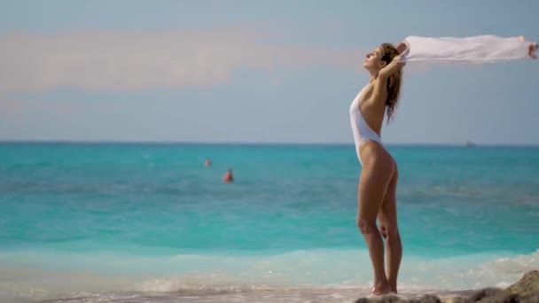 Menina sexy com um pareo branco em desenvolvimento no fundo de um belo mar tropical — Vídeo de Stock