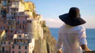 Şapkalı kız Manarola şehir İtalya arka plan üzerinde duruyor