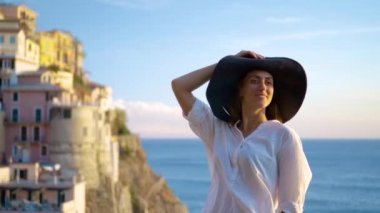 Şapkalı kız Manarola şehir arka planı gülümsüyor